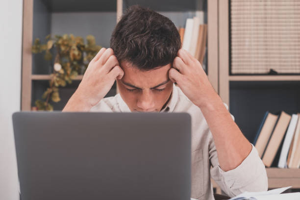 istock Unhealthy stressed young man suffering headache at home because overwork and studying hard for exams. Tired male teenager doing homework for school 1372122534