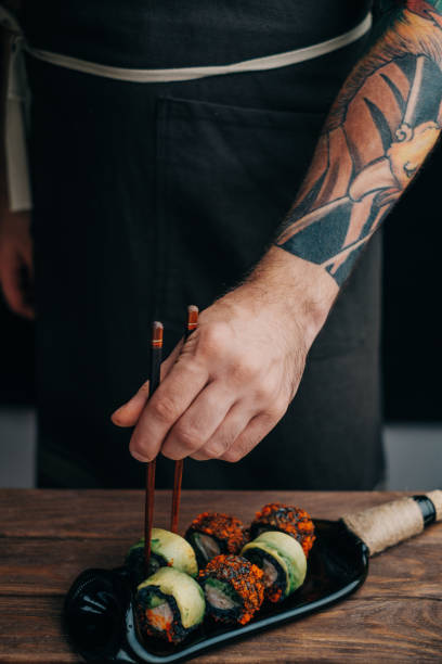 istock Chef takes one sushi roll with chopsticks. 1372122543