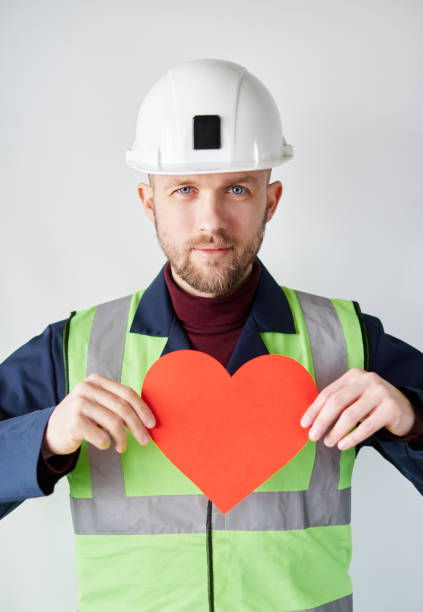 istock Construction Day: male worker in hard hat showing red heart 1372123293