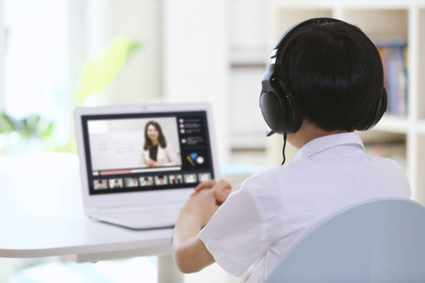 istock Young student wearing wireless headphones and taking online class on laptop 1372123407