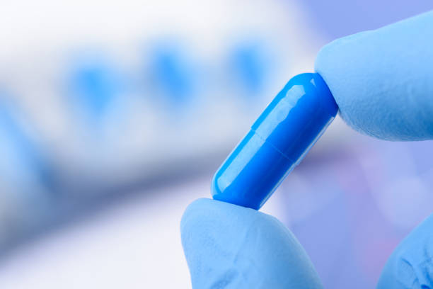 istock Scientist hold in fingers blue pill capsule 1372123919