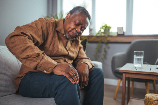 istock An African mature man suffers from knee pain while sitting on a couch. 1372124010