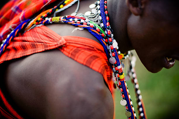 Maasai Warrior in Traditional Clothing and Jewelry This is an African Maasai Warrior dressed in his traditional clothing.  He is in the Serengeti National Park wearing home-made Maasai jewelry and his earlobes are stretched as is tradition with the Maasai. maasai mara national reserve photos stock pictures, royalty-free photos & images