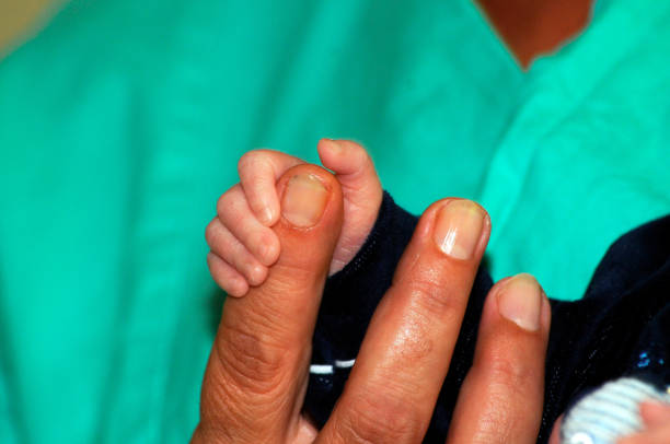 hand of a newborn touching finger of a nurse in hospital