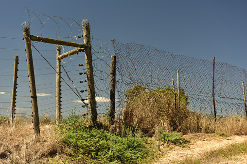 Brooklyn, New York, NY, USA - July 6th 2022: High and strong fence with barbed wire on top in a industrial part of Brooklyn