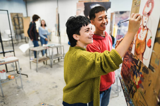 Multiracial students painting inside art room class at school - Focus on girl face stock photo