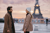 Couple, man and woman standing in front of Eiffel Tower, looking at each other