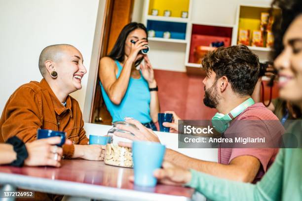 Group of young people having breakfast at coffee bar of an hostel, friends talking and having fun together at living room, diverse gen z people at brunch on vacation