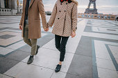 Couple holding hands while walking on Parvis des Droits de l'Homme, with Eiffel Tower in background