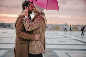 Romantic couple with pink umbrella standing on Parvis des Droits de l'Homme, Paris, kissing
