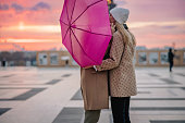 Romantic couple with umbrella kissing at Parvis des Droits de l'Homme, Paris