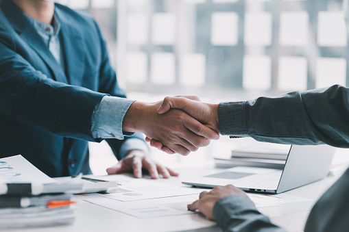Good deal. Close-up of two business people shaking hands while sitting at the working place