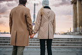 Couple holding hands, looking at Eiffel Tower in the evening, rear view, low angle view