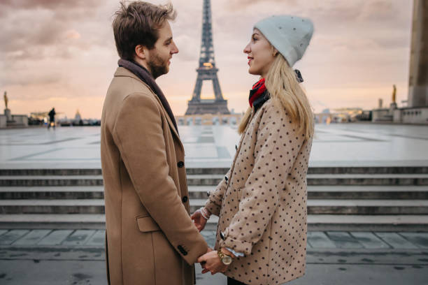 istock Romantic couple looking at each other while holding both hands in front of Parvis des Droits de l'Homme, Paris, with Eiffel Tower in background 1372128084