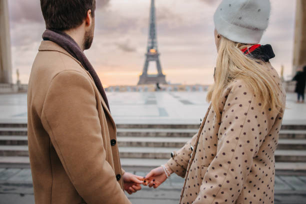 istock Close-up of couple holding both hands while looking at Eiffel Tower, Paris, in the evening 1372128168