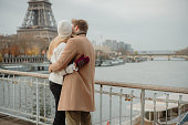 Romantic couple hugging and kissing at Seine River with Eiffel Tower, Paris, in the background
