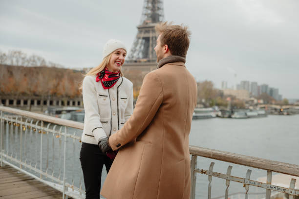 istock Couple smiling while standing on a bridge at Seine River with Eiffel tower, Paris, in the background 1372128955