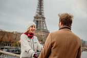 Close-up of blond woman smiling at her boyfriend, holding hands in front of Eiffel Tower