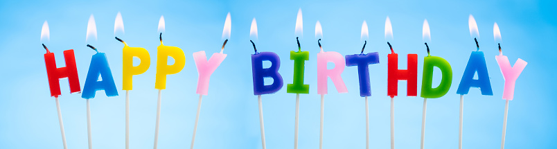 Colorful Candles on a  Blue Background that Spell Happy Birthday