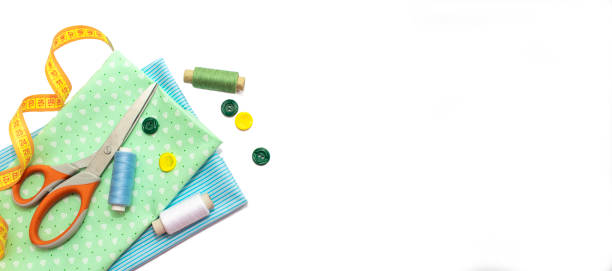 istock Sewing accessories, blue and green fabric on white background. Threads, needles, fabric, buttons and sewing centimeter. 1372130058