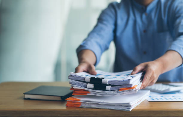istock Businessman Preparing reports papers with graphs, charts on Stacks of documents files for finance in office. Piles unfinished achieves with paper clip near computer. Concept of Business Annual Report. 1372132896