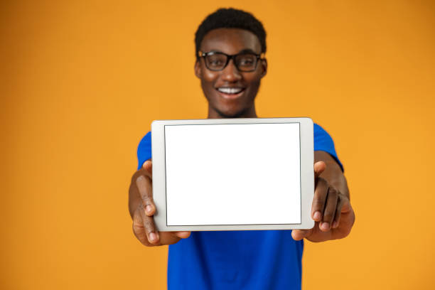 istock African american man showing blank digital tablet screen with copy space in yellow studio. 1372133261