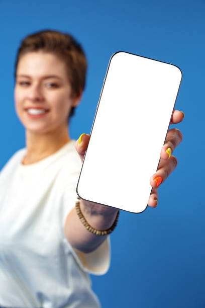 istock Happy woman shows blank smartphone screen against blue background 1372133958