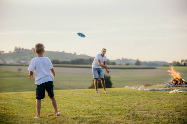 istock Father throws a frisbee to his little son during a campfire at sunset 1372134034