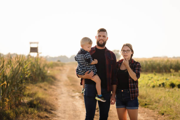 istock Couple with son looking at camera while standing on a country lane next to agricultural fields 1372134151
