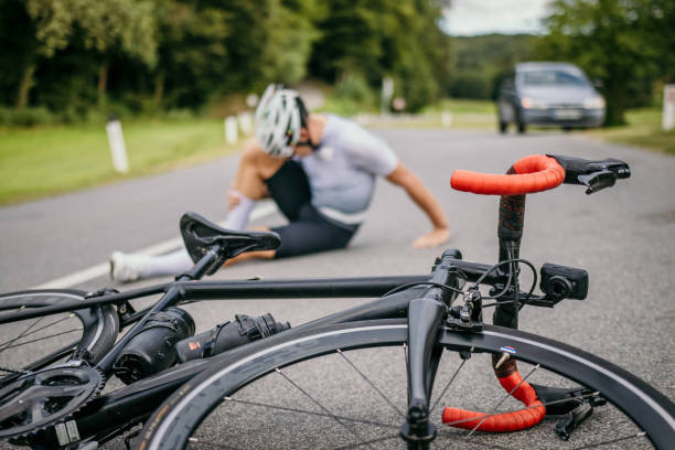 ciclista ferito seduto nel dolore accanto alla bicicletta da corsa - helmet motorized sport biker crash helmet foto e immagini stock