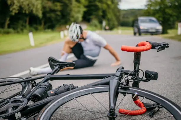 Photo of Injured cyclist sitting in pain next to the racing bicycle