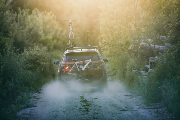 Off-road car carrying mountain bikes on a rack in the middle of the forest Off-road car with mountain bikes on a rack driving on a country road in the middle of the forest. bicycle rack photos stock pictures, royalty-free photos & images