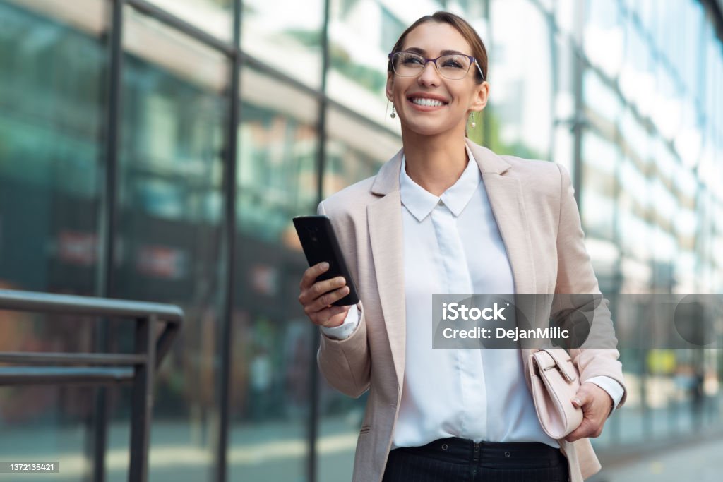 Woman layer walking outdoor and holding phone in hand Street Stock Photo