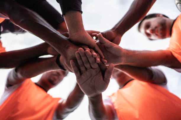 jogadores empilhando as mãos no campo de futebol - team sport sports team sport community - fotografias e filmes do acervo