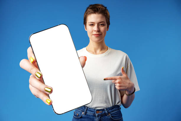 istock Happy woman shows blank smartphone screen against blue background 1372135769