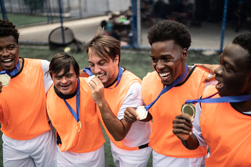 Players celebrating winning a medal on the soccer field - including a person with special needs
