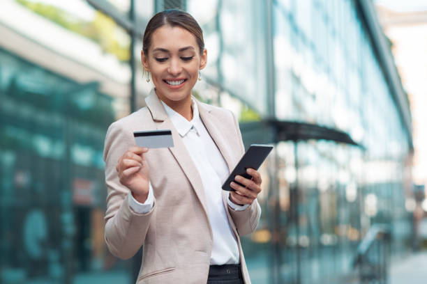 Business woman holding credit card and using phone stock photo
