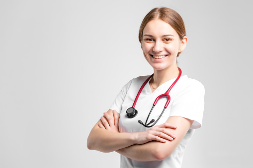 Beautiful caucasian doctor in white medical uniform with stethoscope at the studio. Copy space for your design. Studio portrait, concept with white background.