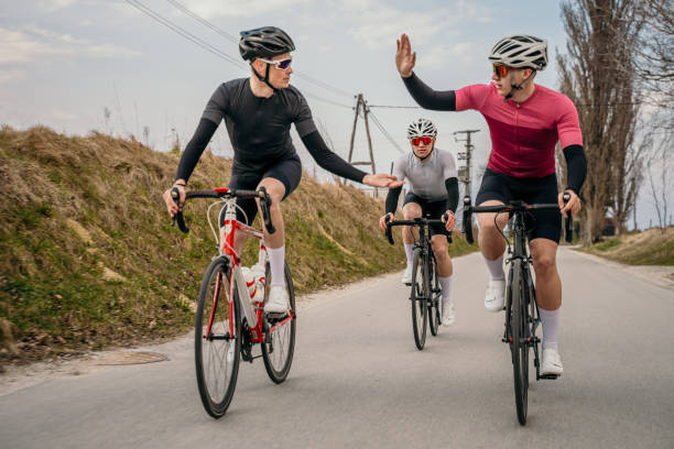 coéquipiers cyclistes donnant cinq high five tout en faisant du vélo - racing bicycle cycling professional sport bicycle photos et images de collection