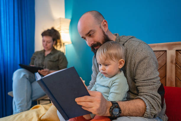 istock Caring father reading a fairy tale to his son, while mother using digital tablet 1372137203