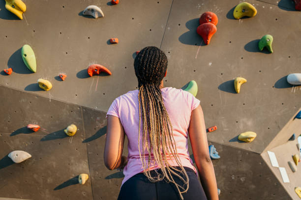 Teenage girl doing indoor climbing seen from below.