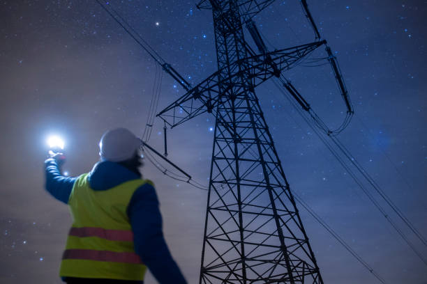 High voltage engineer working at night on the field. Sustainable energy. stock photo