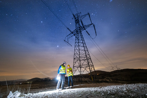 Electrical engineers working on electrical pylons translation at night. Team solving issues.