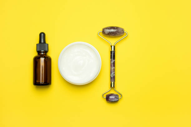 istock Face roller with cosmetic serum and face cream on a yellow background. 1372140239