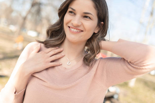 retrato de una mujer feliz y hermosa poniéndose el collar de plata - heart pendant fotografías e imágenes de stock