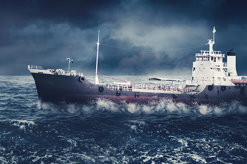 Image of cargo ship sailing on the storm sea with cloudy sky background