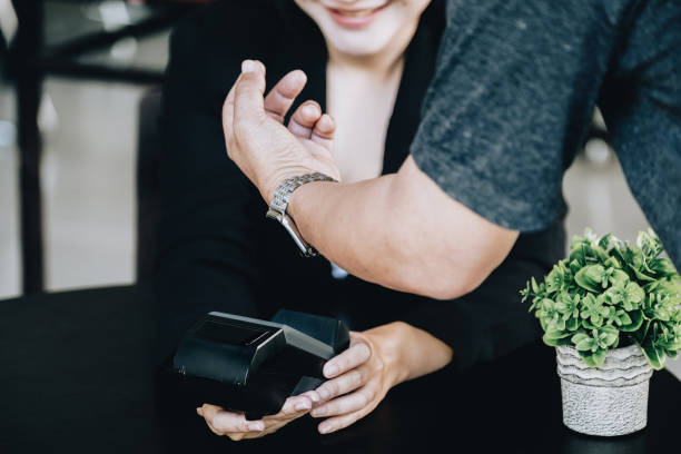 istock Payment security technology concept and service fees, Employees are holding electronic card machines for customers to use smartwatches to pay via paywave technology. 1372150733
