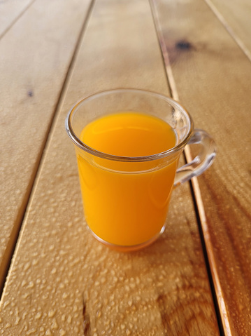 glass of orange juice on wet wooden table
