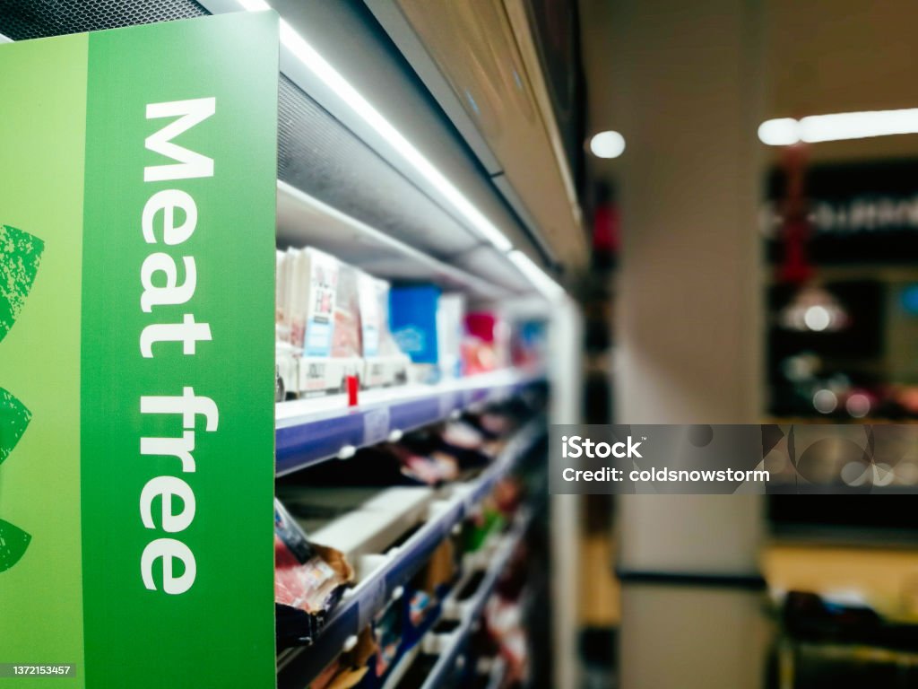 Meat Free sign in the supermarket Sign in a supermarket aisle with the words 'meet free'. Focus on the sign with the supermarket shelves defocused beyond. Veganism Stock Photo