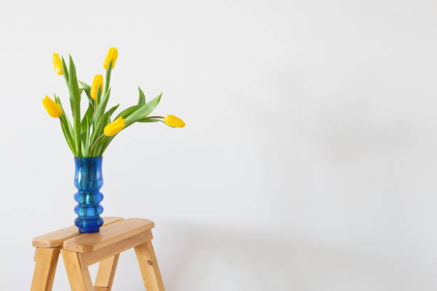 istock yellow tulips in blue glass vase on white background 1372157298